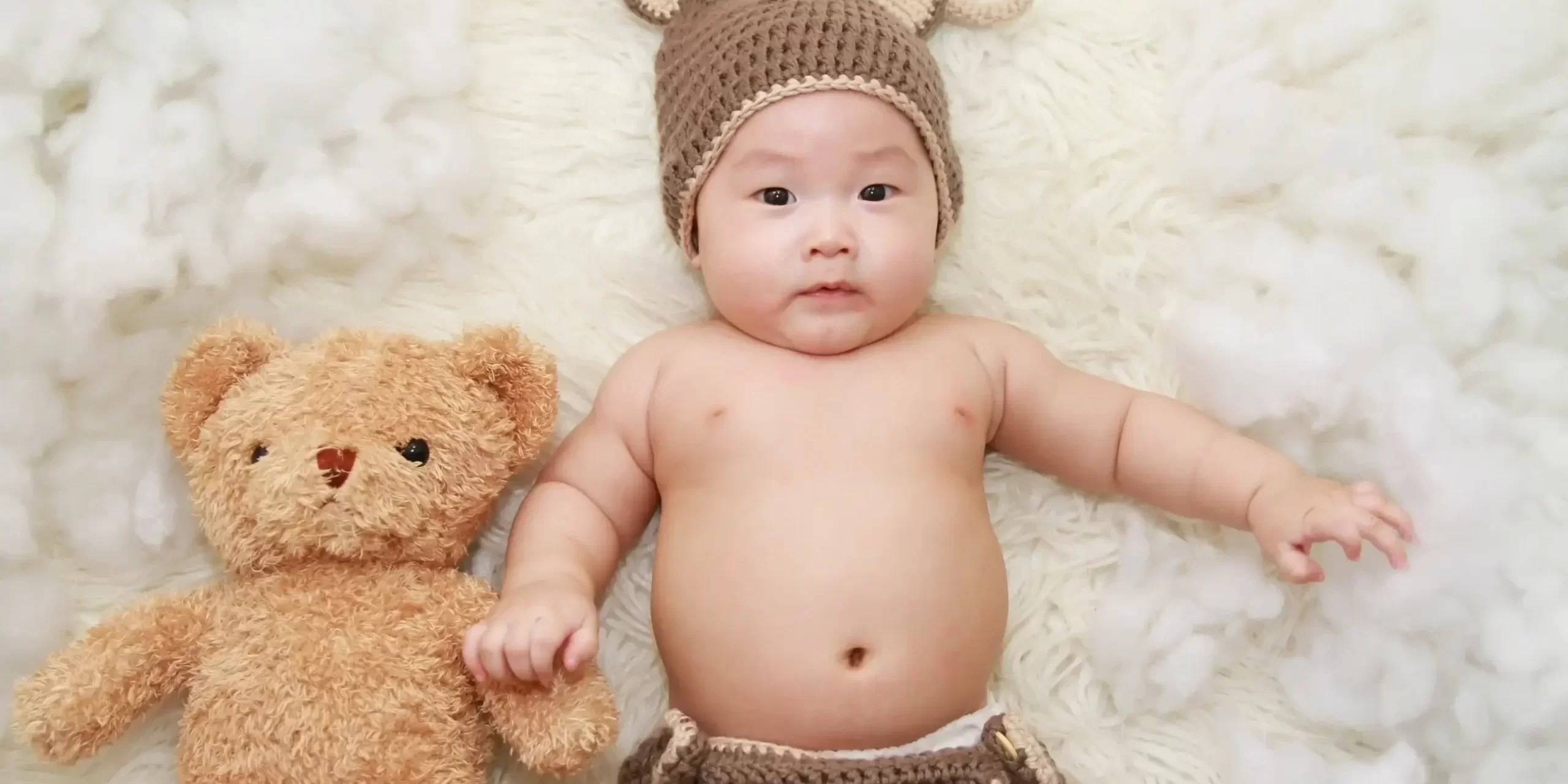 Bébé éveillé sur un lit avec un ours en peluche